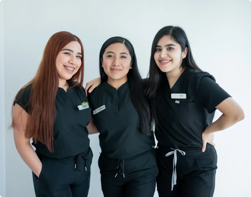 mujeres con ropa de dentista posando y sonriendo para la camara