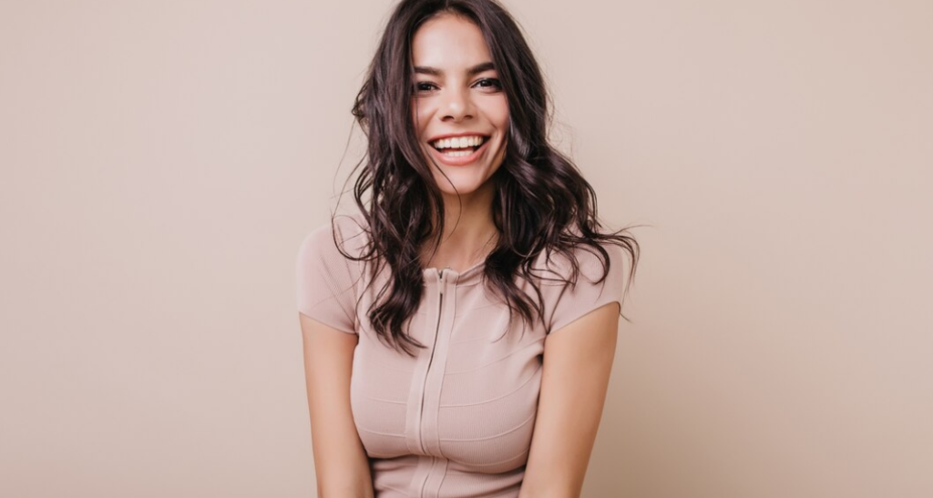 mujer sonriendo para una foto y vistiendo color beige