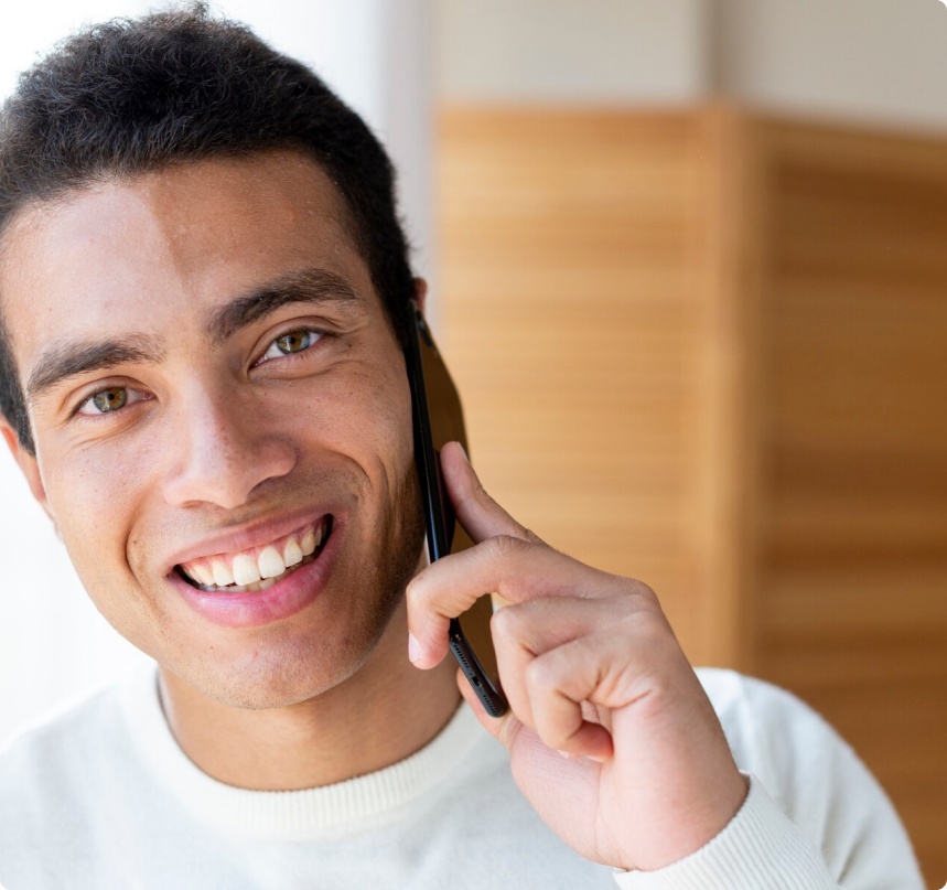 hombre joven hablando por celular y vistiendo una camiseta color blanco.
