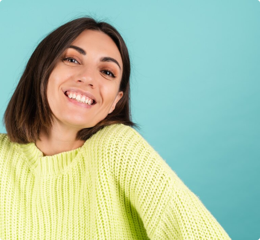 mujer sonriendo para unaf oto y vistienod un sueter color verde.